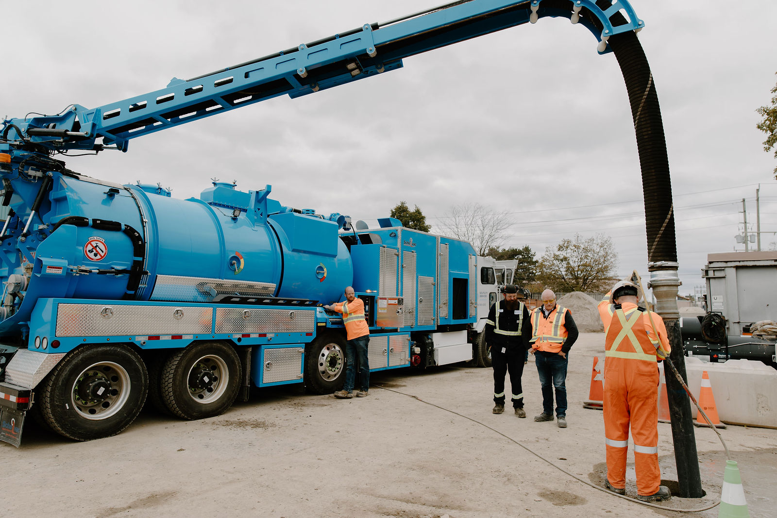 An OE crew working with the hybrid hydrovac truck's boom over a dig